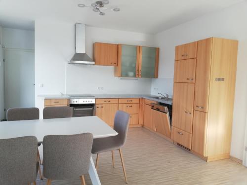una cocina con armarios de madera, mesa y sillas en Gemütliches 3 Zimmer Apartment nahe Graz, en Gratkorn