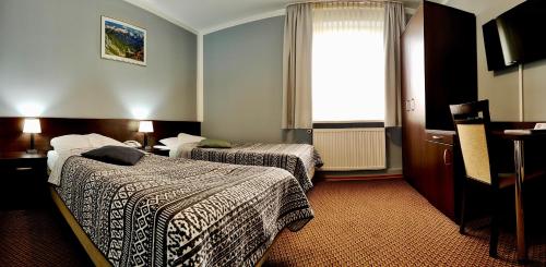 a hotel room with two beds and a window at Hotel Pawłowski in Zgorzelec
