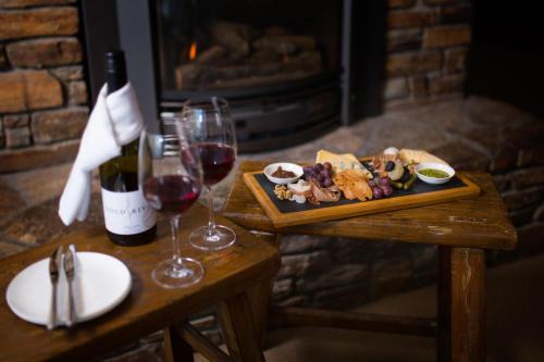 Hidden Lodge Queenstown في كوينزتاون: طاولة مع طبق من الطعام وزجاجة من النبيذ