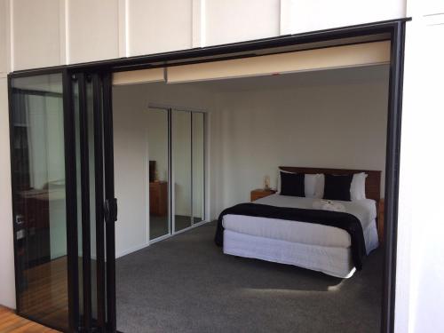 a bedroom with a bed and a large glass door at Trendy Bungalow in the Heart of Rotorua in Rotorua