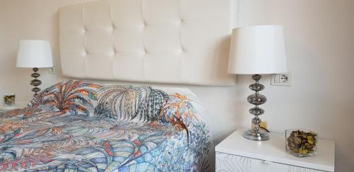 a bedroom with a bed with a white headboard and two lamps at Balcon Del Mar Luxury Suite in Costa Del Silencio