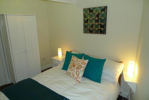 Schlafzimmer mit einem Bett mit grünen und weißen Kissen in der Unterkunft Courtyard Cottage in Knaresborough
