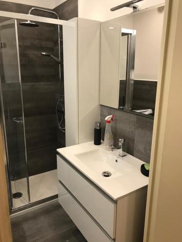 une salle de bain avec un lavabo blanc et une douche dans l'établissement Menton smartworking and relax on the beach, seaview, à Menton