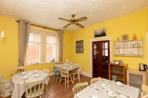 a dining room with two tables and a ceiling fan at The Osprey Hotel in Blackpool