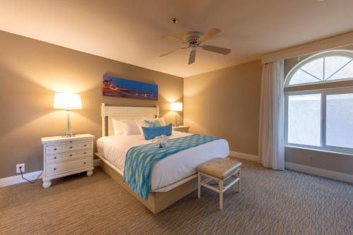 a bedroom with a bed with a ceiling fan and a window at Capistrano SurfSide Inn in Capistrano Beach