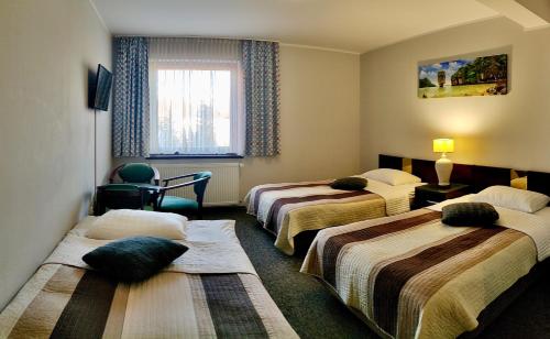 a hotel room with three beds and a window at Hotel Pawłowski in Zgorzelec