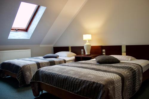 two beds in a attic room with a window at Hotel Pawłowski in Zgorzelec