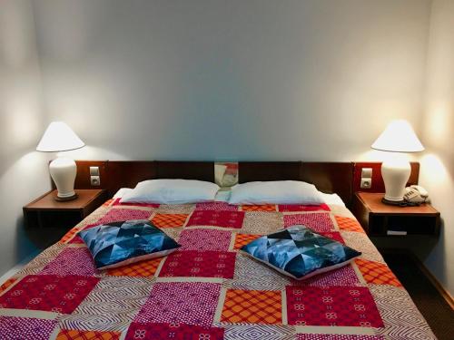 a bed with two pillows on it with two lamps at Hotel Pawłowski in Zgorzelec