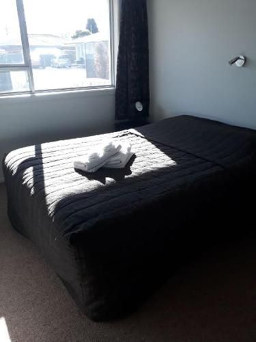 a bed in a bedroom with a window at Aalton Motel Temuka in Temuka