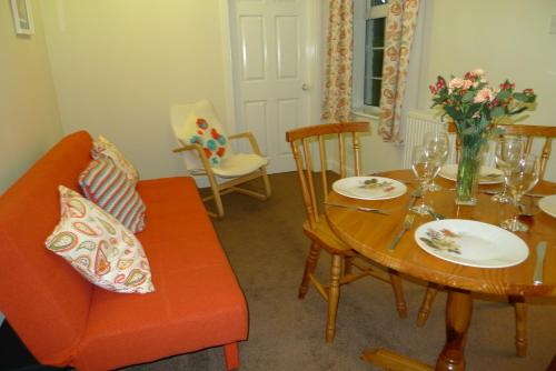 ein Wohnzimmer mit einem Tisch und einem orangefarbenen Sofa in der Unterkunft Courtyard Cottage in Knaresborough