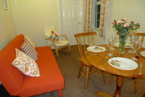 un soggiorno con tavolo e divano arancione di Courtyard Cottage a Knaresborough