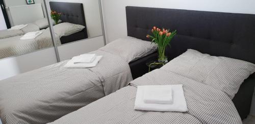 two beds in a room with a vase of flowers at OPAL z widokiem na morze w Gardenia Sea Side Dziwnów in Dziwnów