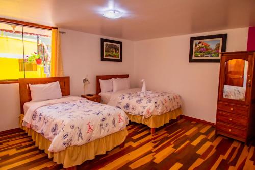 a bedroom with two beds and a dresser at Intitambo Hotel in Ollantaytambo
