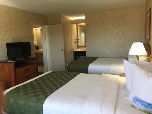 a hotel room with two beds and a television at Days Inn & Suites by Wyndham Albuquerque North in Albuquerque