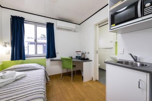 mały pokój z łóżkiem i umywalką w obiekcie Jolly Swagman Acccommodation Park w mieście Toowoomba