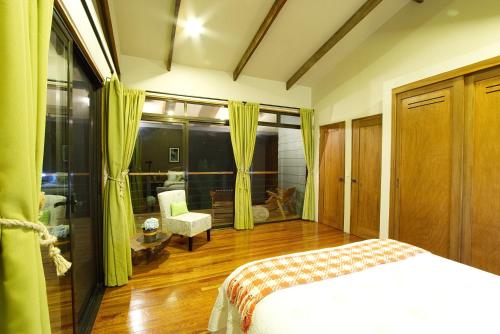 a bedroom with a bed and a chair in a room at Monteverde Casa Mia, near main attractions and town! in Monteverde Costa Rica