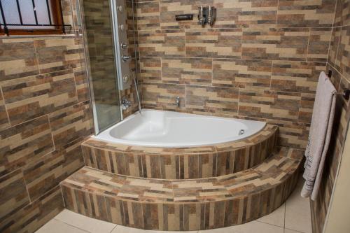 a bath tub in a bathroom with a shower at DYNA GUEST HOUSE in Durban