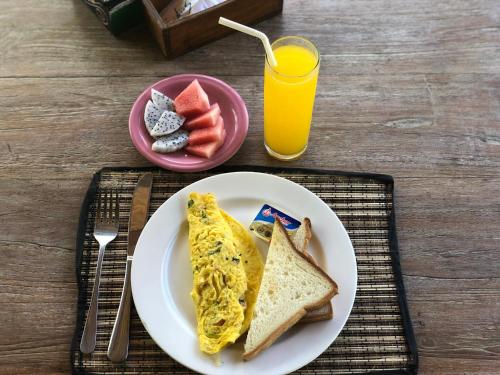 een ontbijtbord met eieren en toast en een glas sinaasappelsap bij D'Waktu in House in Nusa Lembongan