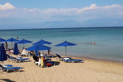 a beach with blue umbrellas and people in the water at MAREMA 2 in Kómpoi