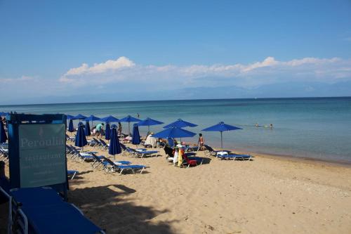 a beach with blue umbrellas and people on the beach at MAREMA 2 in Kómpoi