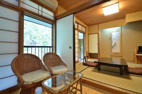 a living room with chairs and a table on a balcony at Kurokawa Onsen Oku no Yu in Minamioguni