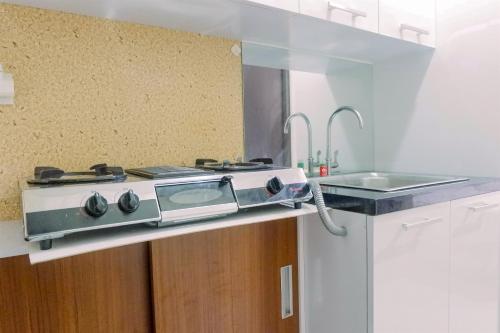 a kitchen with a stove and a sink at Compact Studio Room at Tamansari Papilio Apartment By Travelio in Surabaya