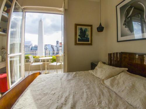 a bedroom with a bed and a window with a view at Penthouse frente al Obelisco con terraza in Buenos Aires