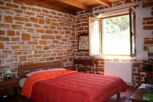 a bedroom with a red bed in a brick wall at PETRA-MARE in Triopetra