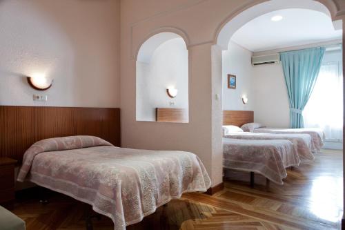 a room with three beds and a mirror at Hostal Zamora in Madrid