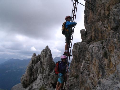 two people on a ladder on the side of a mountain at Hotel Garni Civetta in Selva di Cadore