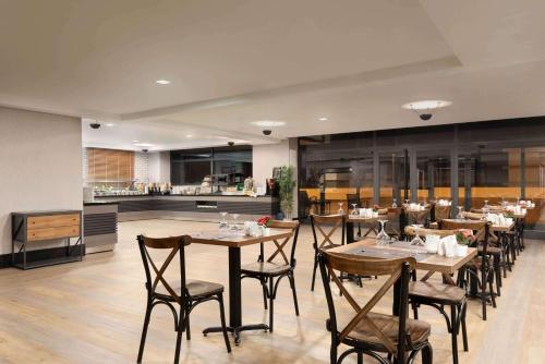 a restaurant with wooden tables and chairs and a kitchen at Ramada By Wyndham Tire in Tire