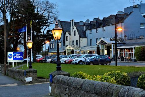 a street light with cars parked in a parking lot at Best Western Kings Manor in Edinburgh