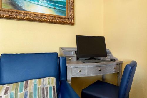 a desk with a computer and a blue chair at Days Inn by Wyndham Port Aransas TX in Port Aransas
