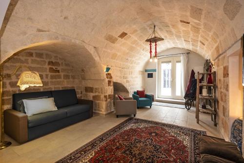 een woonkamer met een bank en een stenen muur bij Eremo Guest House-Housea Travel in Polignano a Mare