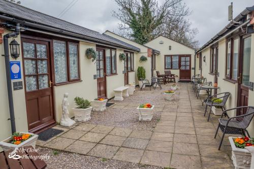 a courtyard of a house with chairs and tables at The Farmers Boy Inn Guest House in Longhope