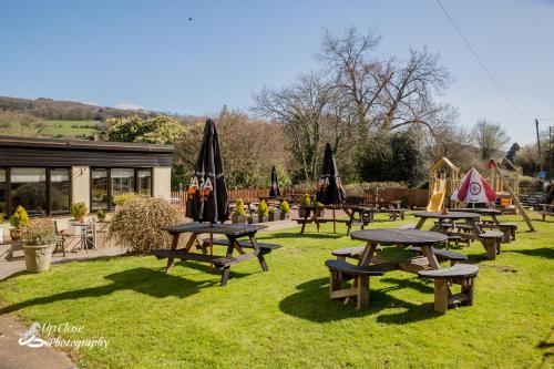 a group of picnic tables in the grass with umbrellas at The Farmers Boy Inn Guest House in Longhope