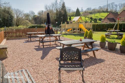 a park with picnic tables and an umbrella and a playground at The Farmers Boy Inn Guest House in Longhope
