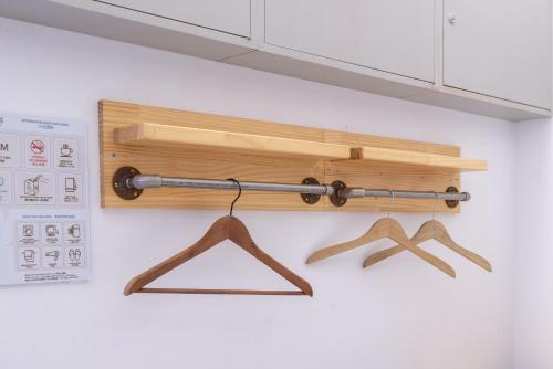 a shelf with two wooden hangers on a wall at May Rooms Taipei Main Station in Taipei