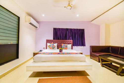 um quarto com uma cama, uma televisão e um sofá em FabHotel Pentagon Airport em Bhubaneshwar