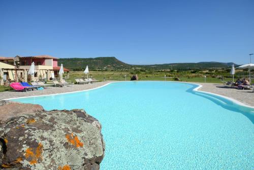 a large blue swimming pool with a rock at Hotel Sa Cheya Relais & Spa in Alghero