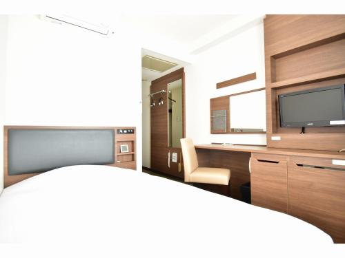 ein Zimmer mit Schreibtisch, Fernseher und Stuhl in der Unterkunft Hotel New Amami in Amami