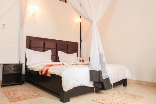 1 dormitorio con 1 cama grande con sábanas blancas en Hotel Kangaroo Bujumbura, en Buyumbura