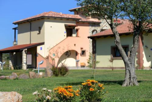 a house with a tree and flowers in a yard at Hotel Sa Cheya Relais & Spa in Alghero