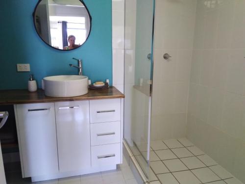 a bathroom with a sink and a shower with a mirror at Cosy, self-contained and central to everywhere in Gold Coast