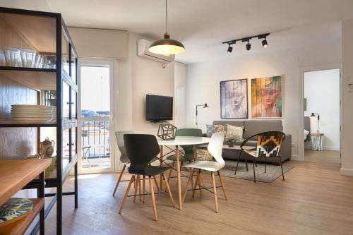 a dining room and living room with a table and chairs at SUNN Amador de los Ríos, by Homing U in Seville