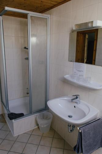 a white bathroom with a shower and a sink at Pension Lex in Bad Reichenhall