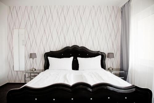 a bedroom with a black and white bed with white pillows at Les Nations in Berlin