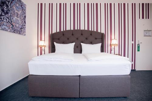 a bedroom with a large white bed with two lamps at Les Nations in Berlin