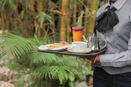 a man is holding a tray of food and a drink at Hotel Kangaroo Bujumbura in Bujumbura