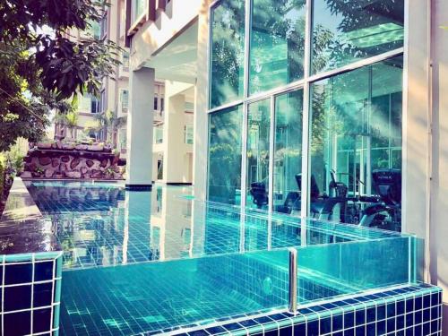 a swimming pool in a building with glass windows at The Lux Ladprao 10 in Bangkok